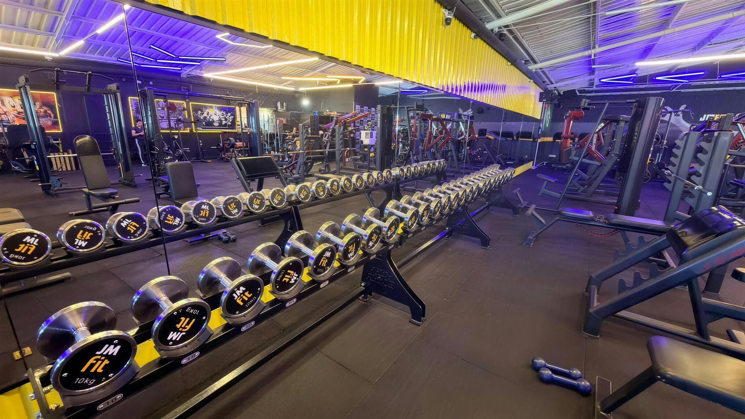 Equipamentos da JMfit com halteres em primeiro plano
