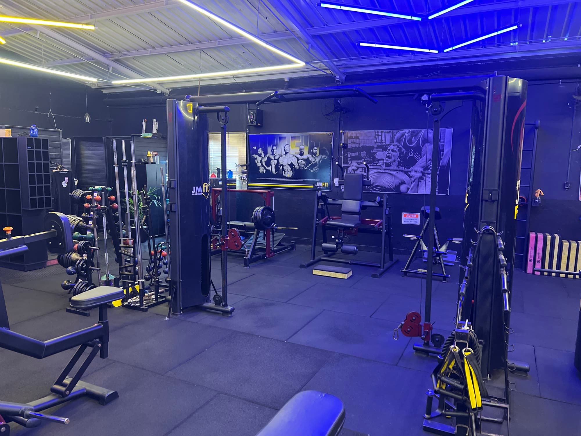 Salão principal da JM Fit com máquinas e painéis de treino